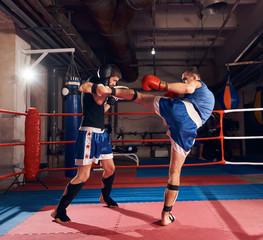 Two active men fighters exercising kickboxing in the ring at the health club