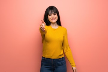 Woman with yellow sweater over pink wall shaking hands for closing a good deal