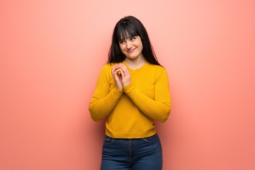 Woman with yellow sweater over pink wall scheming something