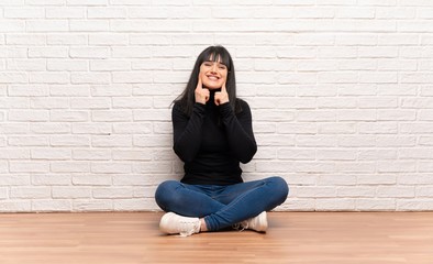 Woman sitting on the floor smiling with a happy and pleasant expression