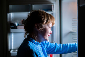 woman by the open refrigerator at night