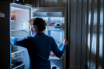 woman by the open refrigerator at night