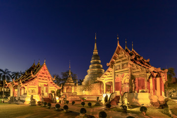 Chapel and golden pagoda at Wat Phra Singh Woramahawihan in Chiang Mai at twilight or night with stars in sky