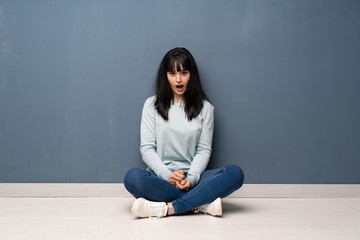 Woman sitting on the floor with surprise facial expression