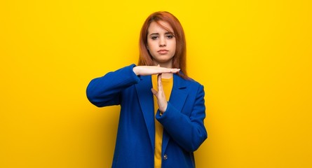 Young redhead woman with trench coat making time out gesture