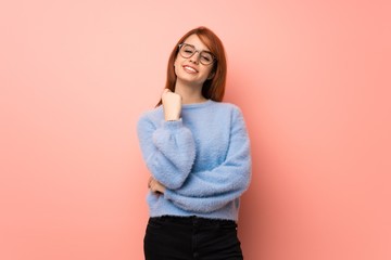 Young redhead woman over pink background with glasses and smiling