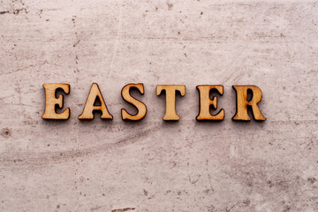 Inscription EASTER in wooden letters on a light background