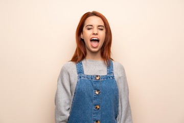 Young redhead woman over isolated background shouting to the front with mouth wide open