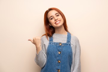 Young redhead woman over isolated background pointing to the side to present a product