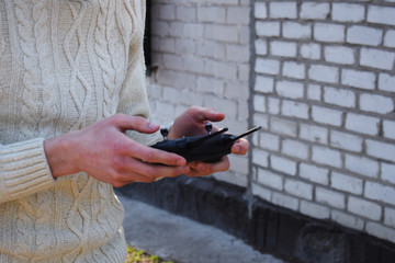 Remote controller in male hands close-up. Man holding transmitter and piloting some vehicle. Drone, rc car or helicopter running. Leisure, hobby, entertainment concept.