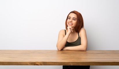 Fototapeta na wymiar Young redhead woman at desk smiling