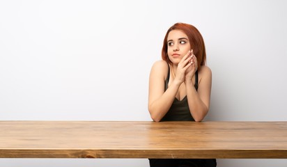 Young redhead woman at desk scheming something