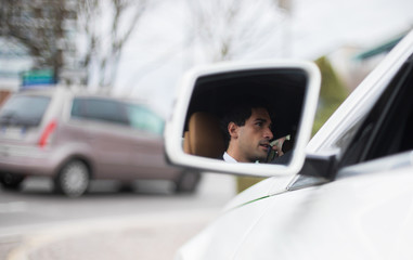 Handsome man driving his car reflected in the mirror