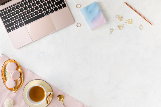 Stylish women's office desk, flat lay. Feminine workspace with, laptop, cup of herbal tea and dessert. Female table on white background. Flatlay, top view