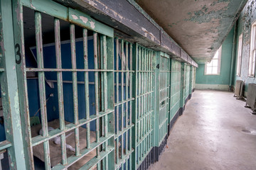 Row of jail cell doors painted green with windows looking outside