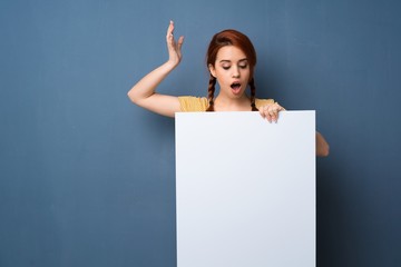 Young redhead woman over blue background holding a placard for insert a concept