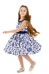 A little girl in a dress is spinning.