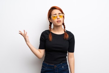 Young redhead woman over white wall making doubts gesture