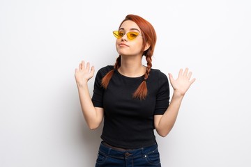 Young redhead woman over white wall making doubts gesture