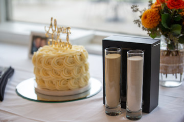 Two jars of sand used for a sand ceremony for a wedding.  the wedding cake is in the background