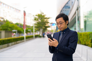 Asian businessman using phone in the city outdoors