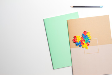 Colorful notebooks and heart made of plastic construction puzzle pieces on white background