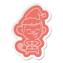 funny cartoon  sticker of a monkey with christmas present wearing santa hat