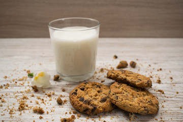 chocolate chip cookies, crumbs and a glass of milk on a wooden table. Rural style