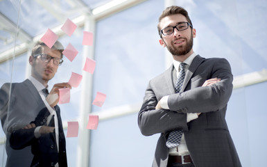 Manager and employee standing near a transparent Board in the office