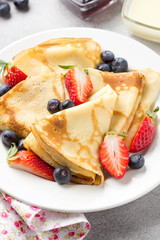 Thin pancakes with strawberries and blueberries, jam, condensed milk, delicious Breakfast. Russian traditional dessert for Shrovetide celebration (maslenitsa). French crepes