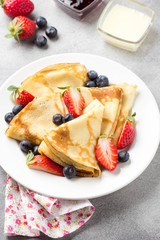 Thin pancakes with strawberries and blueberries, jam, condensed milk, delicious Breakfast. Russian traditional dessert for Shrovetide celebration (maslenitsa). French crepes