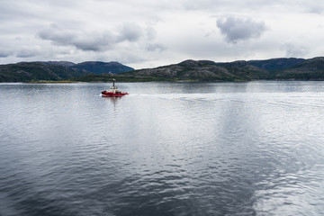 Fishing boat sailing near Norwegian coastline in fjord area, Norway