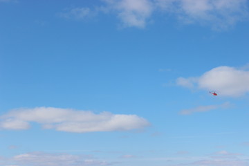 a small helicopter against a blue sky with white clouds on a Sunny day. helicopter flight, emotions as a gift