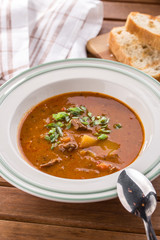 Tomato soup with fresh vegetables and sausages on wooden table