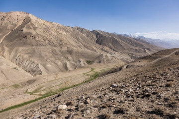 Pamir Highway in the desert landscape of the Pamir Mountains in Tajikistan. Afghanistan is on the left