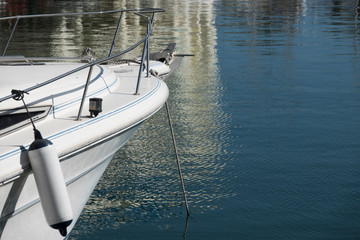 White bow of a moored pleasure boat.  Calm water in the background.