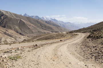 Pamir Highway in the desert landscape of the Pamir Mountains in Tajikistan. Afghanistan is on the left - 254035767