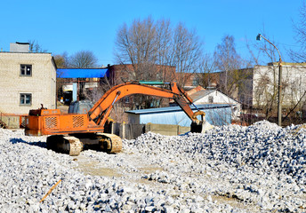 Construction excavator at an industrial gypsum stone processing plant. Excavator bucket loads minerals, gypsum stones, for further processing for building dry mixes for use in building finishing work