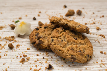 Chocolate chip cookies next to a flower on a wooden table
