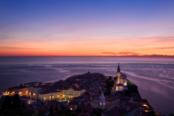 Purple light on the Adriatic Sea after sundown with lights on Piran Slovenia Courthouse City Hall...