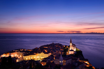 Purple Adriatic Sea after sundown with lights on Piran Slovenia Tartini Square Courthouse City Hall...