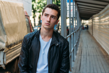 handsome, attractive guy, standing leaning on the railing in a white T-shirt, black, leather...
