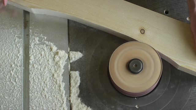 Carpenter at work grinding wood with machine in slow motion close up