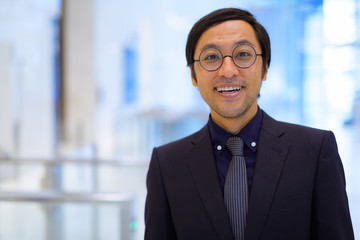 Face of happy Asian businessman smiling inside the office building