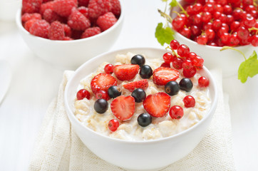 Tasty porridge with strawberry slices, black and red currants