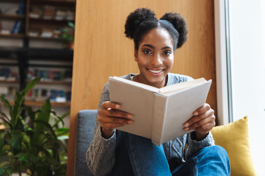 Happy young student girl studying at the library