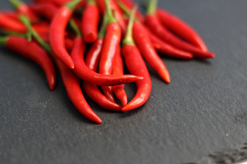 A lot of sharp hot spice red chilli cayenne pepper with wet drops of freshness water dew on a black graphite slate stone surface. Natural vegeterian diet organic vegetable. Dark food foto