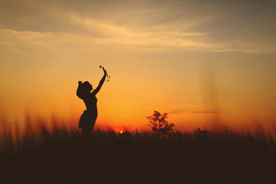 Girl silhouette picks up a flower