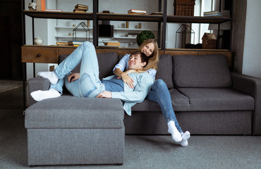 Fototapeta premium Sweet young couple in blue denim cloth playing on the sofa together