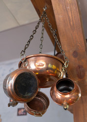 Copper dishes - pots, kettle and bowl hang on the wall.